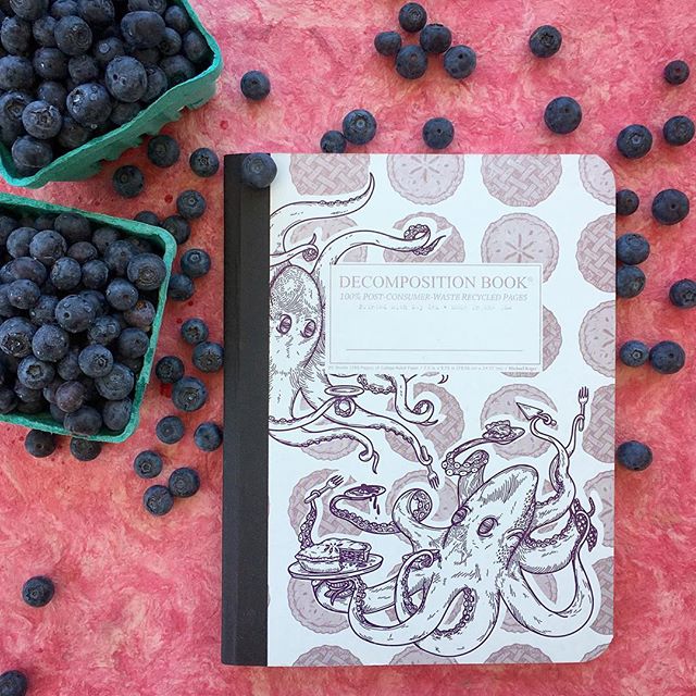 Photo of Decomposition Books notebook with Octopi holding pies on the cover on top of blueberry background