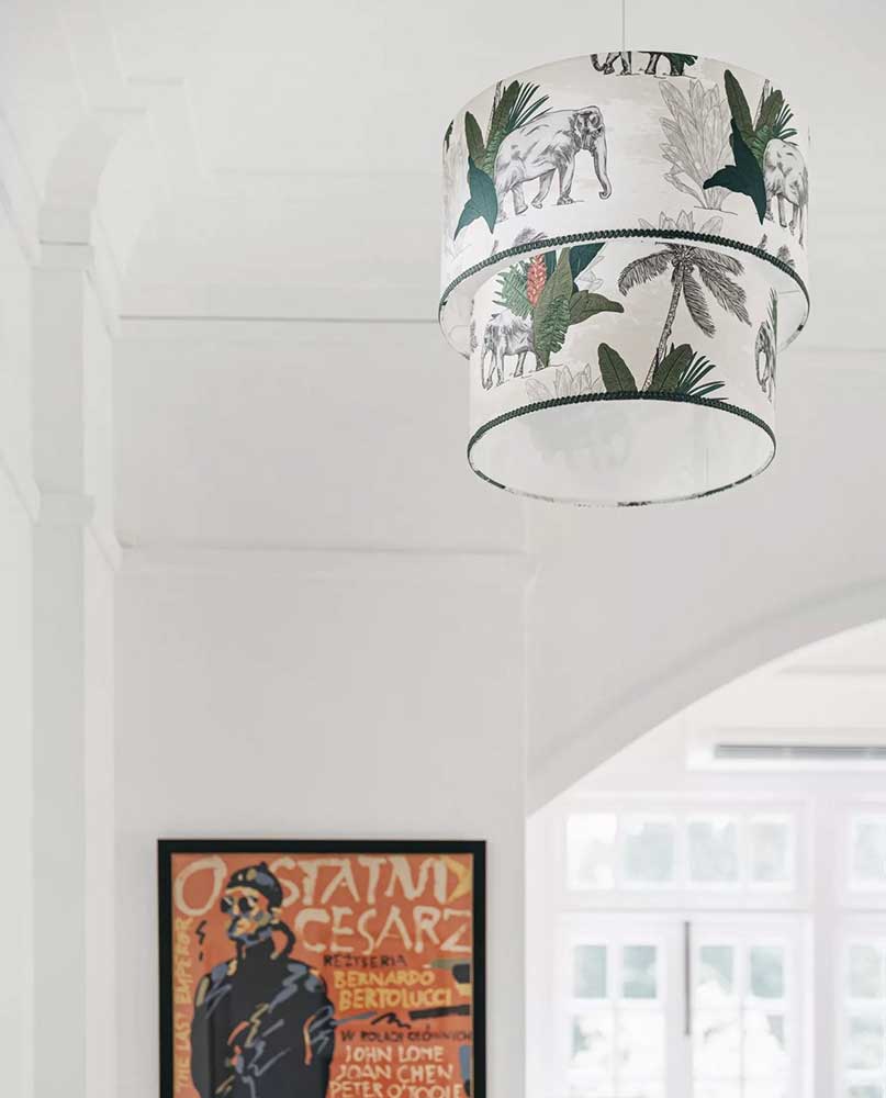 Photo of hanging lampshade with british colonial elephant print on it against wall with poster and window